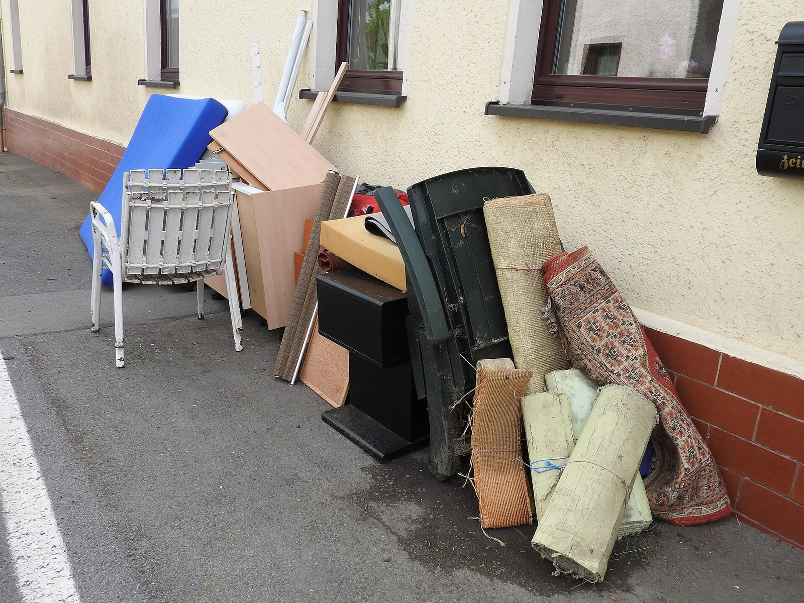 Curbside pile of old furniture, rolled rugs and boxes waiting for a bulky-item pickup